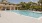 a swimming pool with chairs and a building in the background