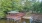 a red building on a dock over water surrounded by trees