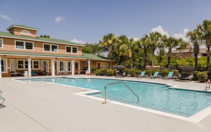 a swimming pool with chairs and a building in the background