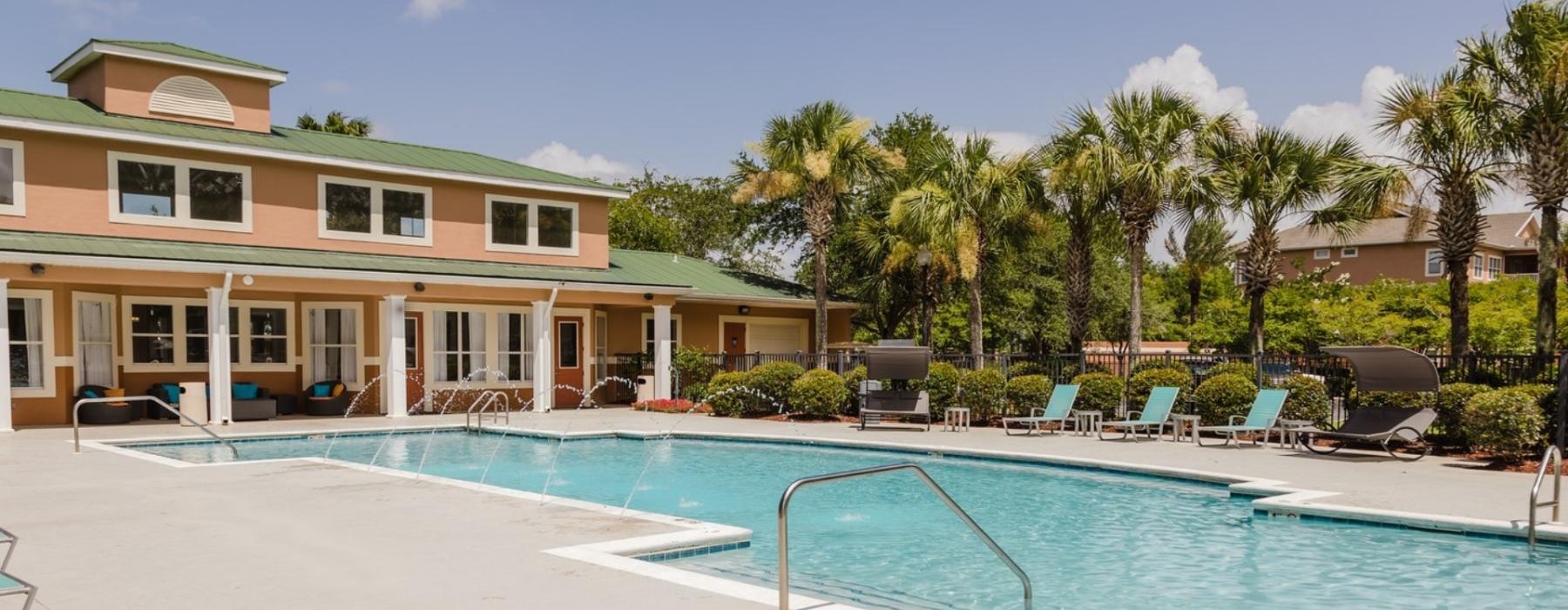 a swimming pool with chairs and a building in the background